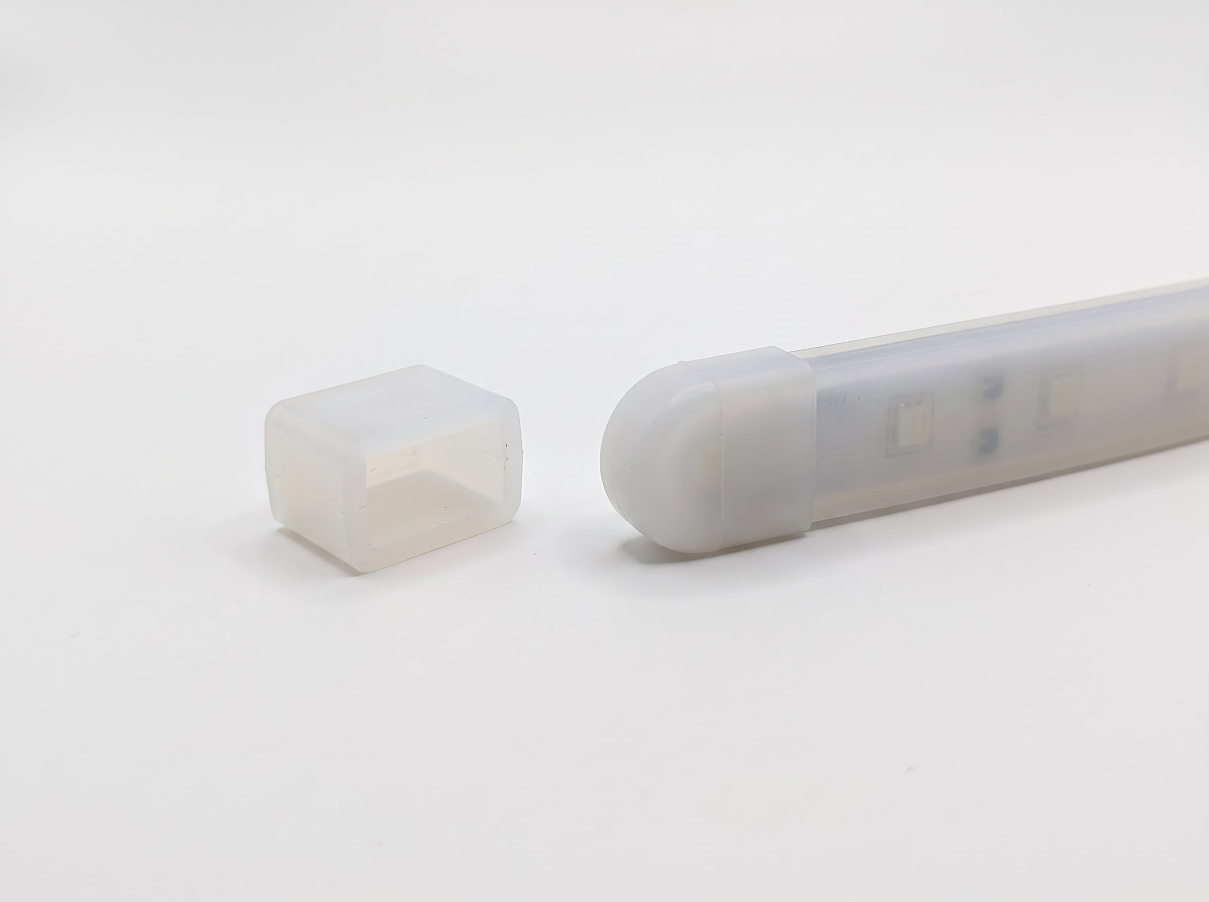 seamless white background featuring a standalone translucent silicone end cap next to a flexible LED light strip equipped with a matching rounded end cap