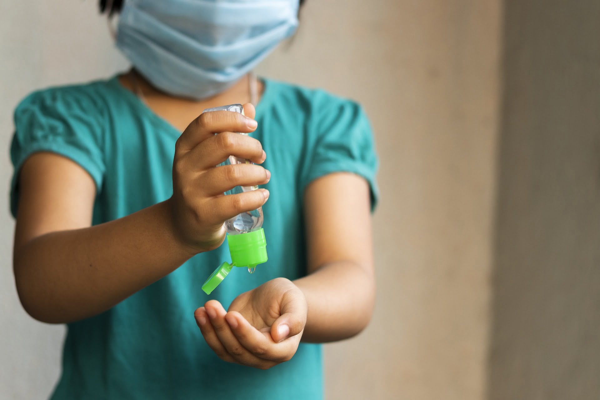 Girl squeezing hand sanitizer gel on her hand.